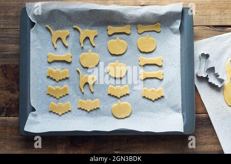 Cookies in various shapes for Halloween on a baking sheet. Cookies cut before baking. Copy space. Stock Photo