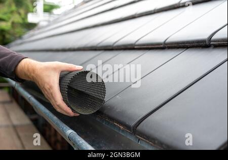 Man puts a gutter mesh to the rain gutter to protect the gutter from leaves. Stock Photo