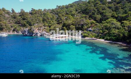 Aerial drone photo of pleasure yacht anchored in crystal clear bay and turquoise beach. uninhabited island in mediterranean sea. Place for swimming in Stock Photo