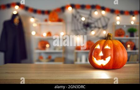 Festive Halloween background with smiley Jack-O-lantern on table in decorated room Stock Photo