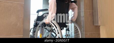 Disabled woman in wheelchair entering elevator back view Stock Photo