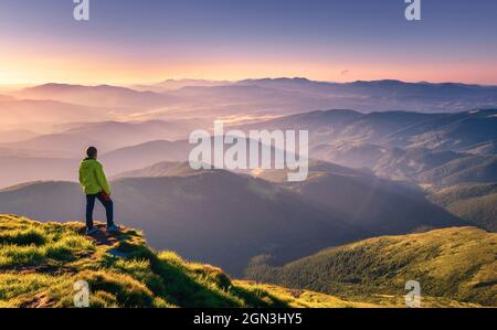 Sporty man on the mountain peak looking on mountain valley Stock Photo