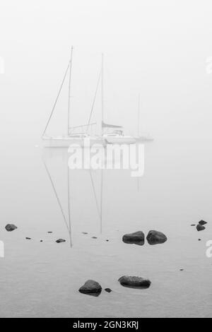 Ghostly yacht reflections in the mist on Windermere Stock Photo