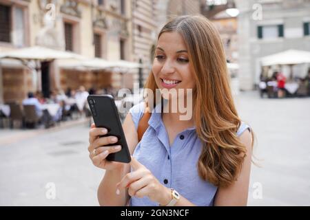 Brazilian smiling woman typing on her telephone outdoors Stock Photo
