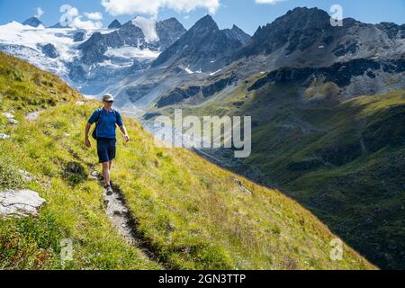 A single male hiker strides out across the Swiss mountains with glaciers in the background. Moiry Valley, Grimentz, Valais Switzerland Stock Photo