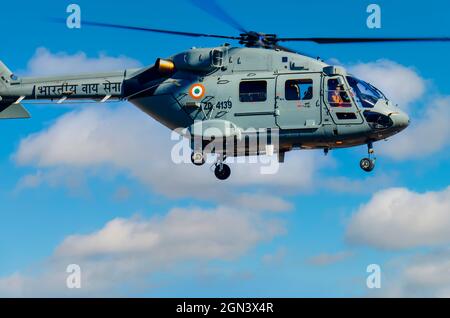 Dhruv, an advanced light helicopter developed by Hindustan Aeronautics Limited's, flies against the backdrop of white puffy clouds. Stock Photo