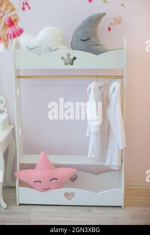 Two white fluffy baby bathrobes on a cute clothes hanger in the nursery. Stock Photo