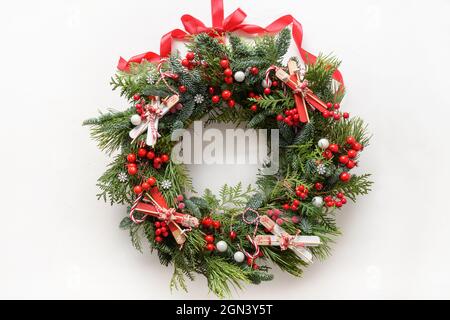 Christmas decorative wreath of natural evergreen branch with holly berries and skiing on white background. New Year. Top view. Traditional decoration Stock Photo