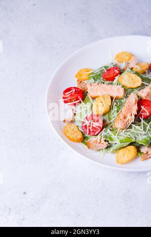 Caesar salad with red fish (salmon, trout), cherry tomatoes, croutons, parmesan cheese and romaine. Traditional American dish. Copy space. Close-up, s Stock Photo