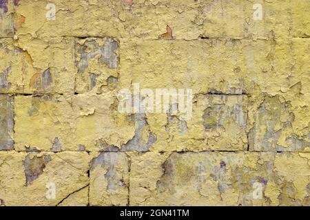 peeled off old yellow paint on flat rough brick wall surface - full frame background and texture Stock Photo