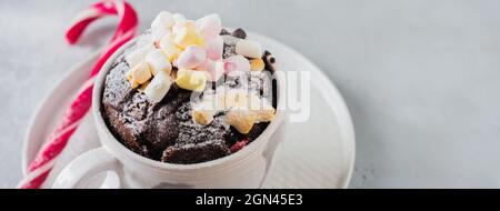 New Year's chocolate cake cooked in microwave oven in mug on vintage gray background texture. Top view. New Year card. Stock Photo