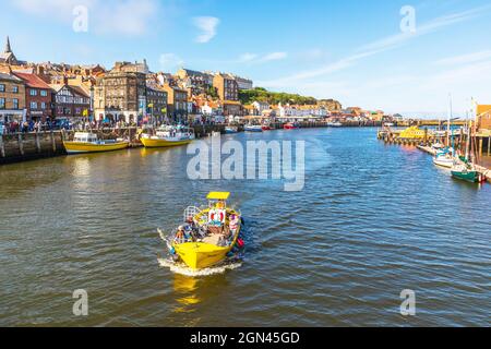 Small motor boat entering the River Esk at the harbour at Whitby, Redcar and Cleveland District, North Yorkshire, England, UK Stock Photo