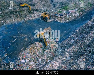 Aerial vie taked with a drone of trash collectors on a garbage deposit, many people live by collecting waste from the mountains of garbage that is generated daily, mostly from the capital of Dhaka.   Bangladesh, the eighth most populous country in the world, currently has a serious pollution problem  due The solid waste generation in urban areas of Bangladesh amounts to around 25,000 tons per day, which translates. The Dhaka city produces one-quarter of all urban waste in the country. The total urban solid waste is projected to grow up to 47,000 tons per day by 2025. On September 22, 2021 in D Stock Photo