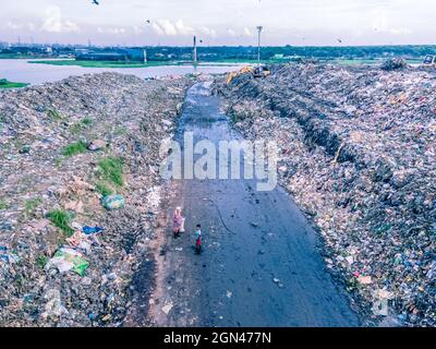 Aerial vie taked with a drone of trash collectors on a garbage deposit, many people live by collecting waste from the mountains of garbage that is generated daily, mostly from the capital of Dhaka.   Bangladesh, the eighth most populous country in the world, currently has a serious pollution problem  due The solid waste generation in urban areas of Bangladesh amounts to around 25,000 tons per day, which translates. The Dhaka city produces one-quarter of all urban waste in the country. The total urban solid waste is projected to grow up to 47,000 tons per day by 2025. On September 22, 2021 in D Stock Photo