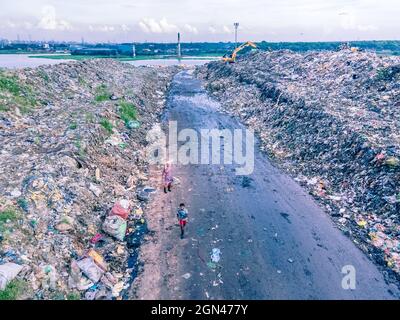 Aerial vie taked with a drone of trash collectors on a garbage deposit, many people live by collecting waste from the mountains of garbage that is generated daily, mostly from the capital of Dhaka.   Bangladesh, the eighth most populous country in the world, currently has a serious pollution problem  due The solid waste generation in urban areas of Bangladesh amounts to around 25,000 tons per day, which translates. The Dhaka city produces one-quarter of all urban waste in the country. The total urban solid waste is projected to grow up to 47,000 tons per day by 2025. On September 22, 2021 in D Stock Photo