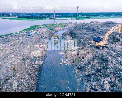 Aerial vie taked with a drone of trash collectors on a garbage deposit, many people live by collecting waste from the mountains of garbage that is generated daily, mostly from the capital of Dhaka.   Bangladesh, the eighth most populous country in the world, currently has a serious pollution problem  due The solid waste generation in urban areas of Bangladesh amounts to around 25,000 tons per day, which translates. The Dhaka city produces one-quarter of all urban waste in the country. The total urban solid waste is projected to grow up to 47,000 tons per day by 2025. On September 22, 2021 in D Stock Photo