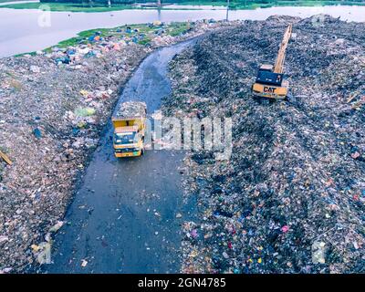 Aerial vie taked with a drone of trash collectors on a garbage deposit, many people live by collecting waste from the mountains of garbage that is generated daily, mostly from the capital of Dhaka.   Bangladesh, the eighth most populous country in the world, currently has a serious pollution problem  due The solid waste generation in urban areas of Bangladesh amounts to around 25,000 tons per day, which translates. The Dhaka city produces one-quarter of all urban waste in the country. The total urban solid waste is projected to grow up to 47,000 tons per day by 2025. On September 22, 2021 in D Stock Photo