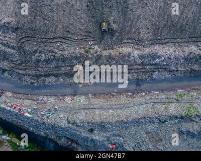 Aerial vie taked with a drone of trash collectors on a garbage deposit, many people live by collecting waste from the mountains of garbage that is generated daily, mostly from the capital of Dhaka.   Bangladesh, the eighth most populous country in the world, currently has a serious pollution problem  due The solid waste generation in urban areas of Bangladesh amounts to around 25,000 tons per day, which translates. The Dhaka city produces one-quarter of all urban waste in the country. The total urban solid waste is projected to grow up to 47,000 tons per day by 2025. On September 22, 2021 in D Stock Photo