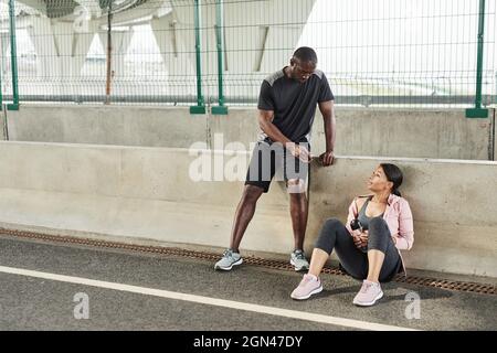Young couple discussing exercises with each other during their training on the stadium Stock Photo