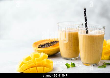 Vegetarian tropical mango papaya smoothie in glass over grey concrete background, copy space for text Stock Photo