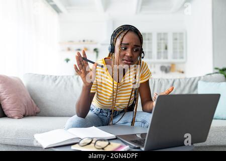 Confused black woman student attending webinar, home interior Stock Photo