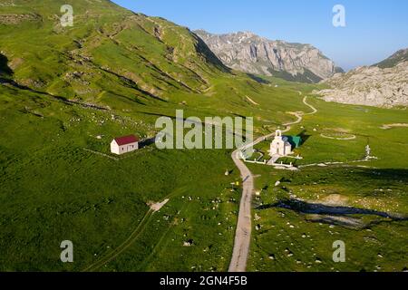 Aerial view of a windy road through beautiful landscape full of flowers and a church of Saint Ilija on Lukavica plateau, Niksic, Montenegro Stock Photo