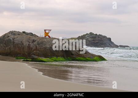 Of a beach formed by an inlet of the sea. Rocks and darker sand and the sighting of a lifeguard house Stock Photo