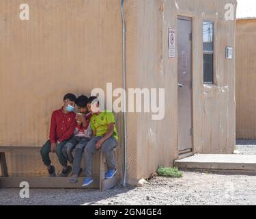 El Paso, United States. 21st Sep, 2021. Afghan children play games on a mobile phone at a temporary camp built in the Dona Ana Complex of Fort Bliss September 21, 2021 in El Paso, Texas. The facility is providing temporary housing, medical screening, and general support for Afghan evacuees. Credit: Sgt. Briaira Tolbert/U.S. Army/Alamy Live News Stock Photo