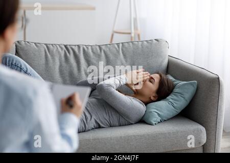 Sad unhappy young caucasian lady patient crying and talking about problems at visit Stock Photo