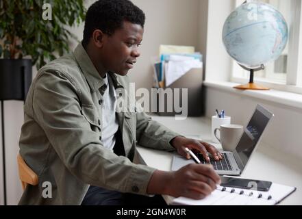 Enthusiastic Young Man Working From Home On Laptop Stock Photo