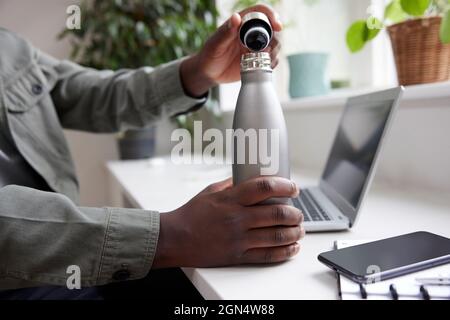 Close Up Of Thirsty Man In Office Opening Reusable Water Bottle For Drink Stock Photo