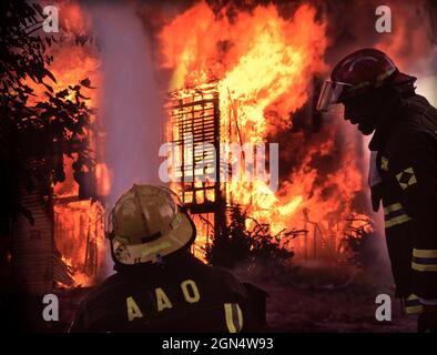 Firemen spraying water on burning house fire Stock Photo