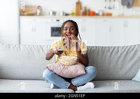 Laughing young black woman watching TV at home Stock Photo