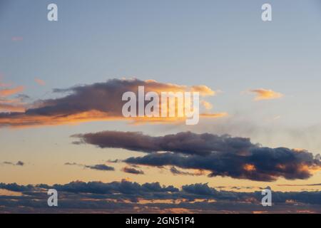 Fiery orange sunset sky. Beautiful perfect sky for your photos. Cloudscape of cumulus sunset clouds with sunlight, evening sky. Heavenly background to Stock Photo