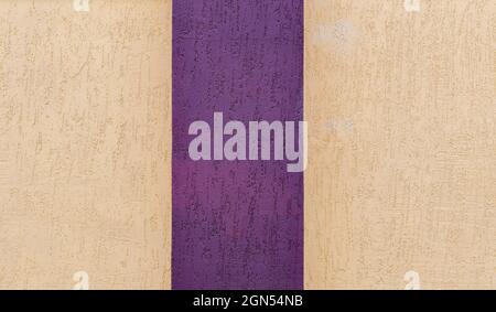 Light beige with purple stripe in middle of textured surface of plastered surface of building. Stock Photo