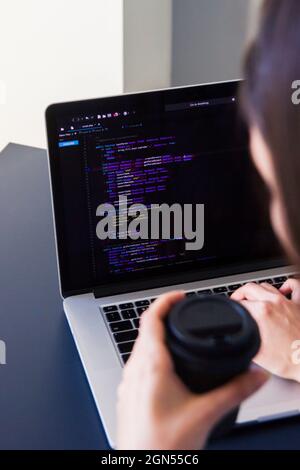 A programmer coding on a laptop in the workplace Stock Photo