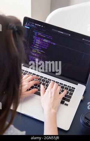 A programmer coding on a laptop in the workplace Stock Photo