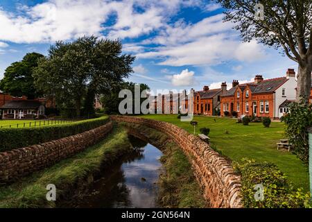 A view of the stream Pow water running through the picturesque village of Powfoot on the Dumfries & Galloway coastline Stock Photo