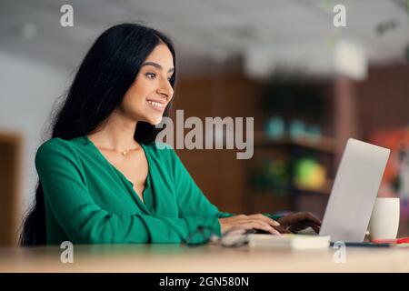Beautiful indian lady chilling at cafe, using laptop Stock Photo