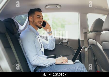 Cheerful businessman working online while going to airport by taxi Stock Photo