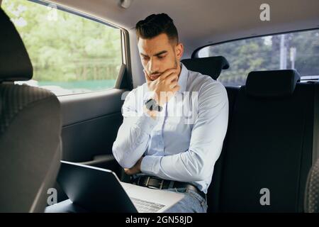 Pensive middle-eastern businessman working at car, using laptop Stock Photo