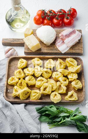 Italian Homemade Tortellini with ingredients, ham, basil, pesto, mozzarella set, on wooden tray, on white background Stock Photo