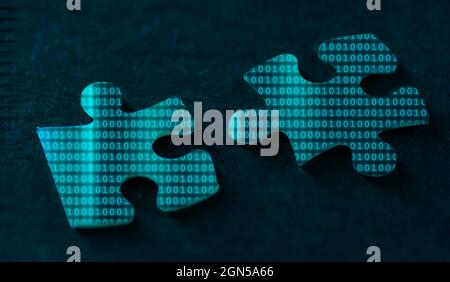 Binary code on two puzzle pieces on a black background Stock Photo