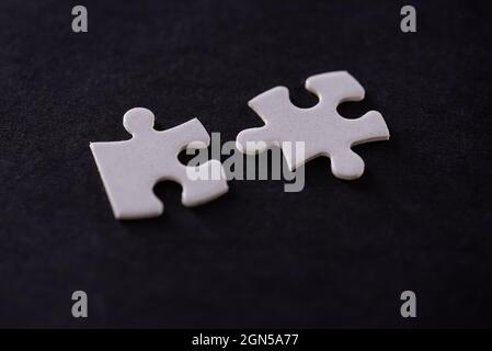 Two white jigsaw puzzles isolated on black background Stock Photo