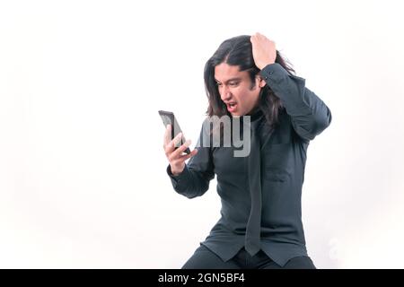 Person with white background. He is holding his hand to his head in frustration, he is very angry about something he has seen on his smart phone. He i Stock Photo