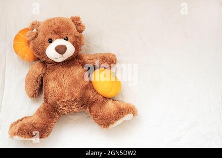 Brown stuffed toy teddy bear with pumpkin on sackcloth fabric texture Stock Photo
