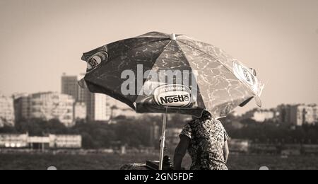 an ice cream saleswoman moves a mobile retail cart branded Nestle along city beach Stock Photo