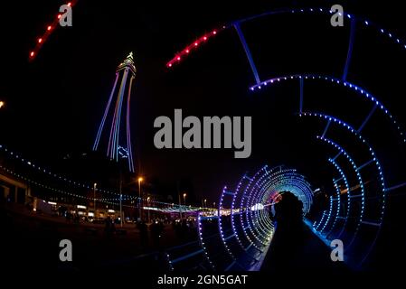 Spiro Light Tunnel and Blackpool Tower at Night, Blackpool Illuminations, September 2021. Spiro Light Tunnel is a  sculptural tunnel of lights. Stock Photo