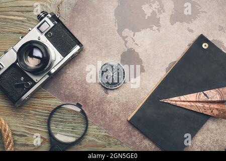World map with photo camera, compass, magnifier and notebook on wooden background Stock Photo