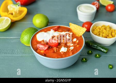 Bowl with tasty chili con carne and ingredients on table Stock Photo